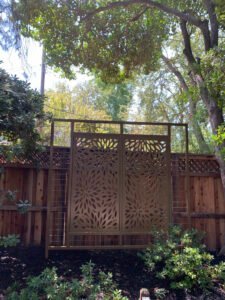 Decorative wooden garden screen among trees and shrubs.