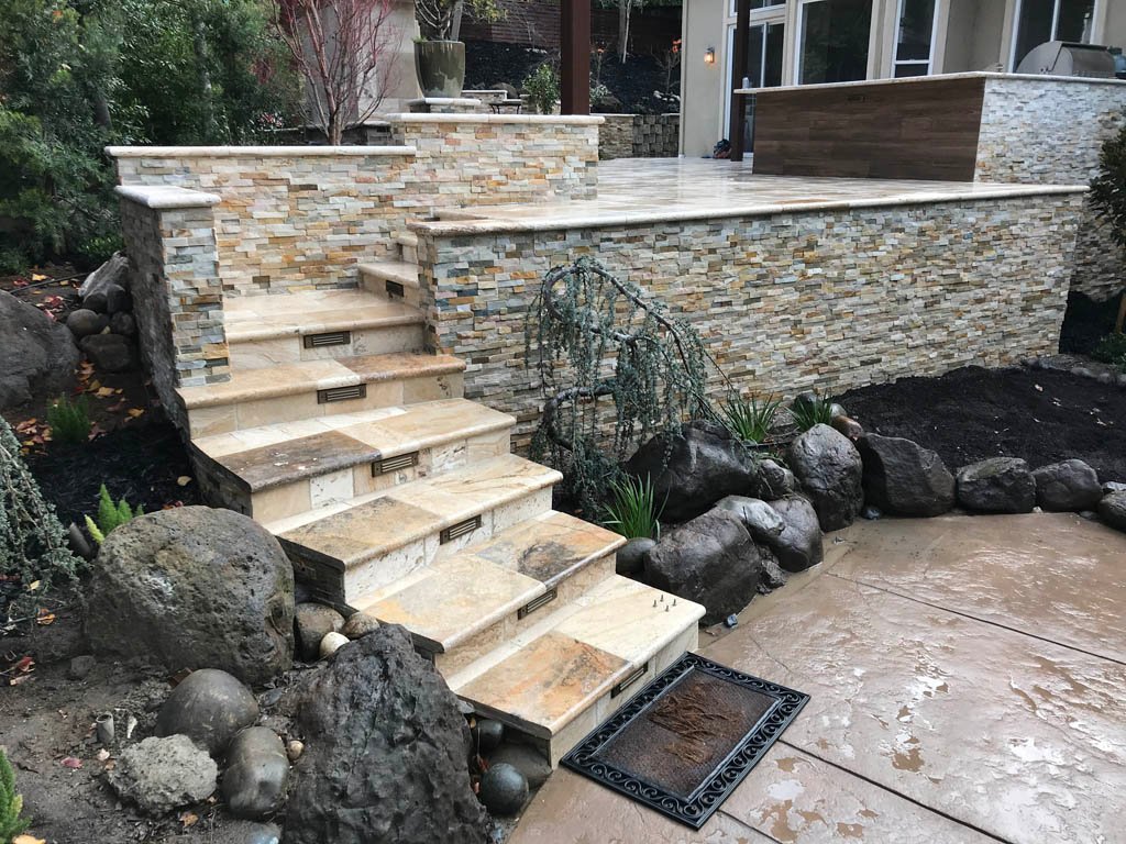 Stone outdoor staircase and wall with landscaped garden.