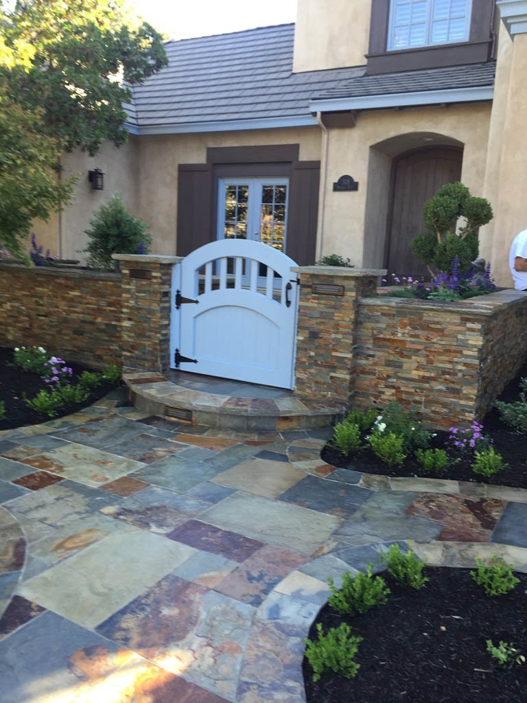 Elegant gated entry to stone house with landscaped path.