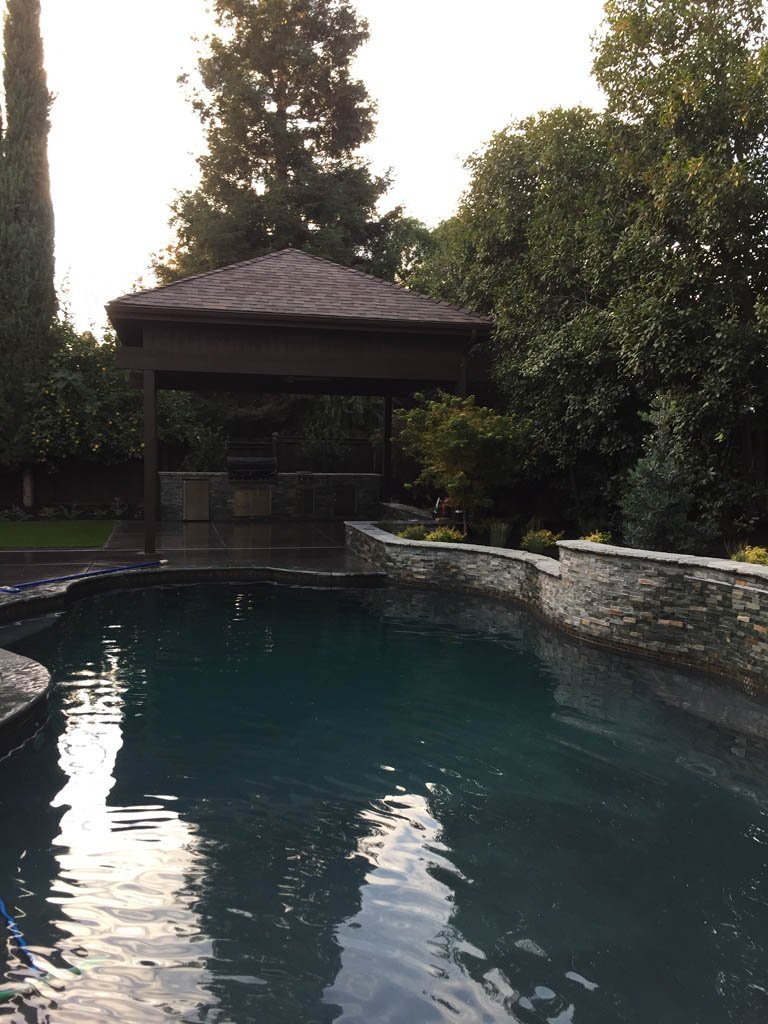 Gazebo by tranquil outdoor pool at dusk.