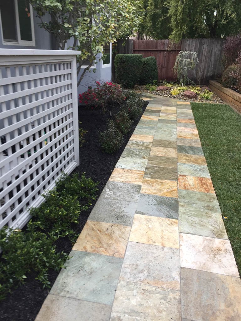 Pathway in landscaped garden with multicolored tiles.