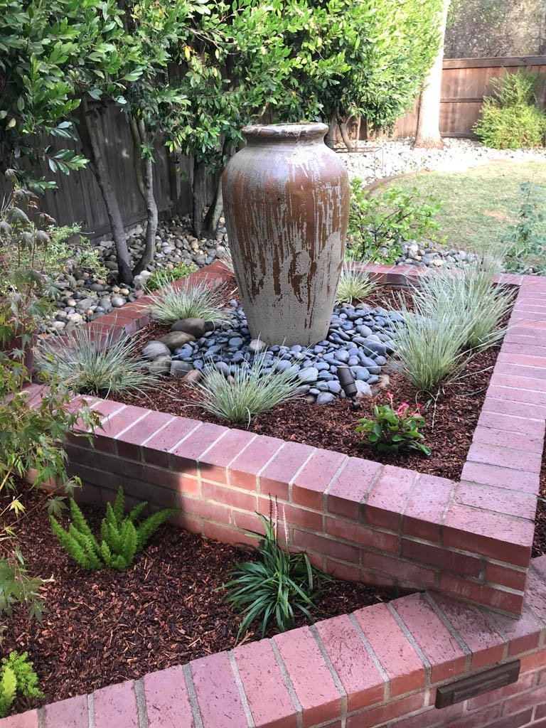 Weathered vase in serene garden with brick and stone details.