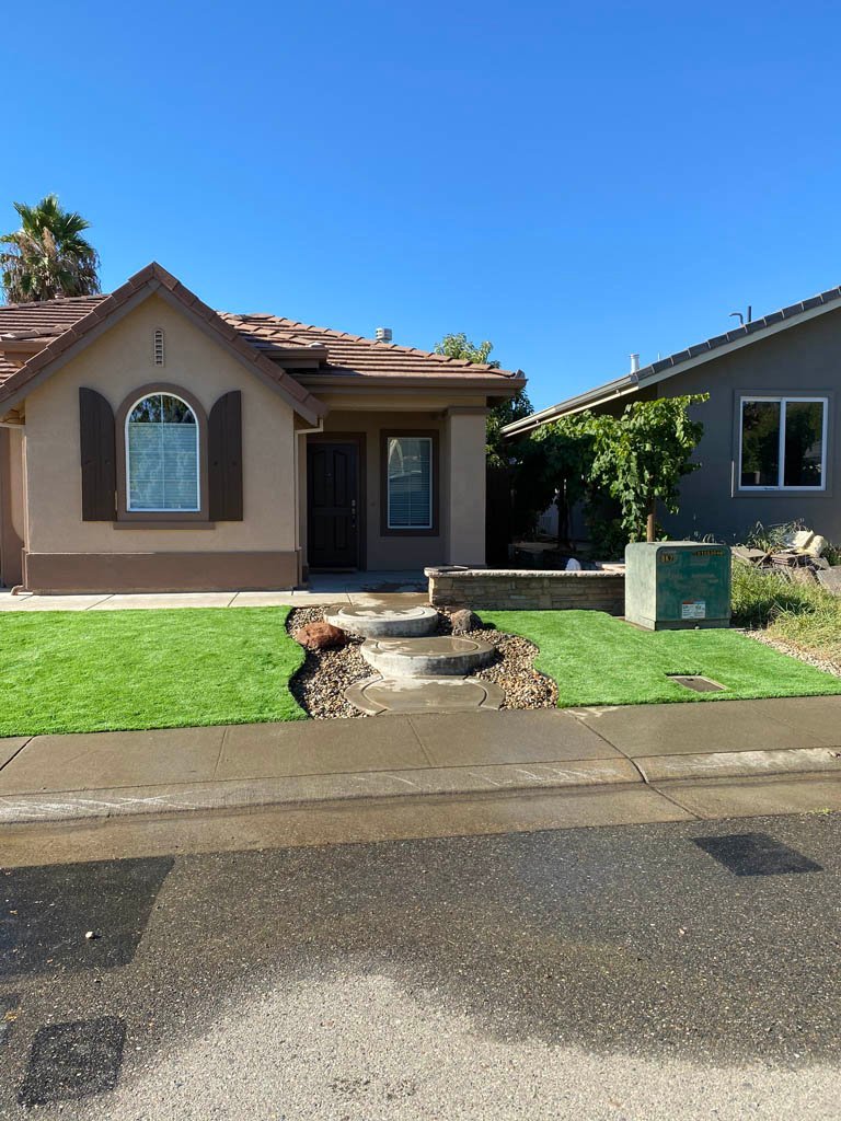 Suburban home with green lawn and decorative fountain.
