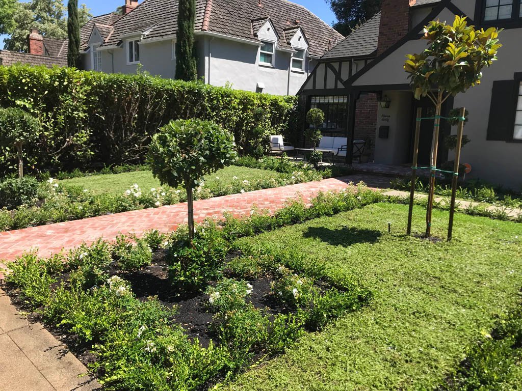 Tudor-style home with landscaped garden and brick pathway.
