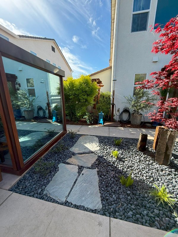 Beautiful backyard garden with stones and mirror by South Canyon Construction