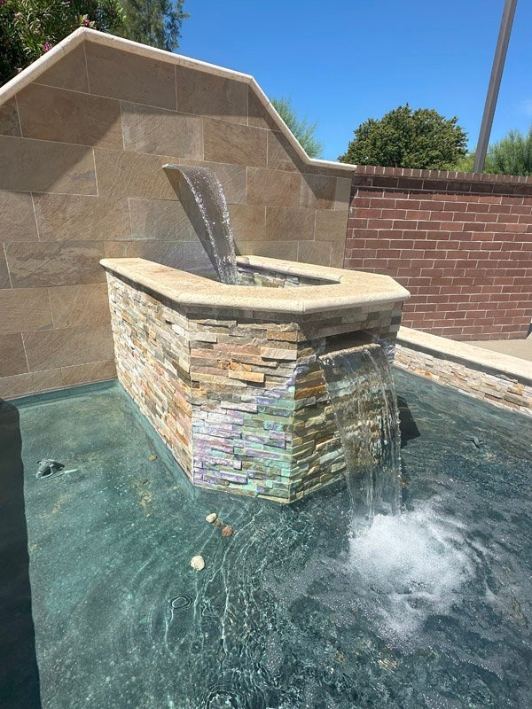 A stylish water feature built by South Canyon Construction showcases cascading water in a serene outdoor setting. The natural stone complements the tranquil atmosphere.