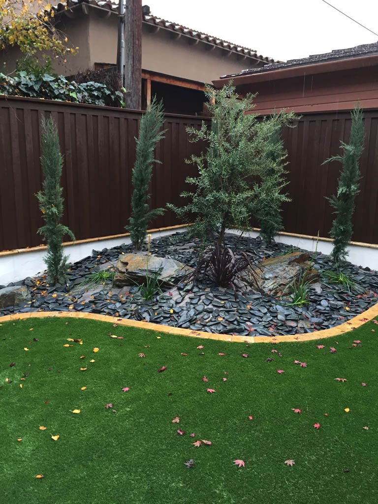 Residential garden with artificial grass and decorative stones.