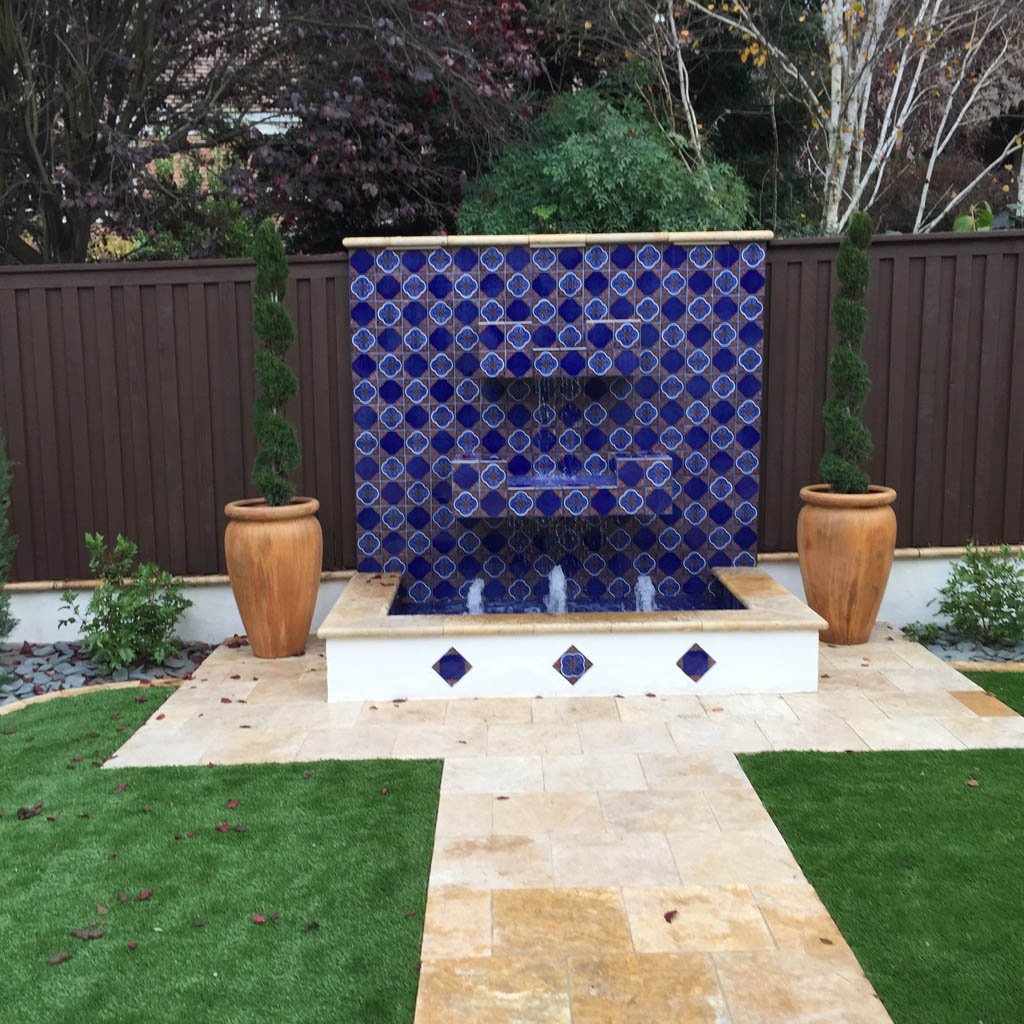 Blue tile fountain with pots in garden setting.