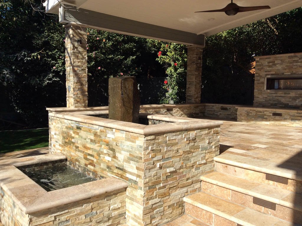 Outdoor patio with stone fountain and fireplace.