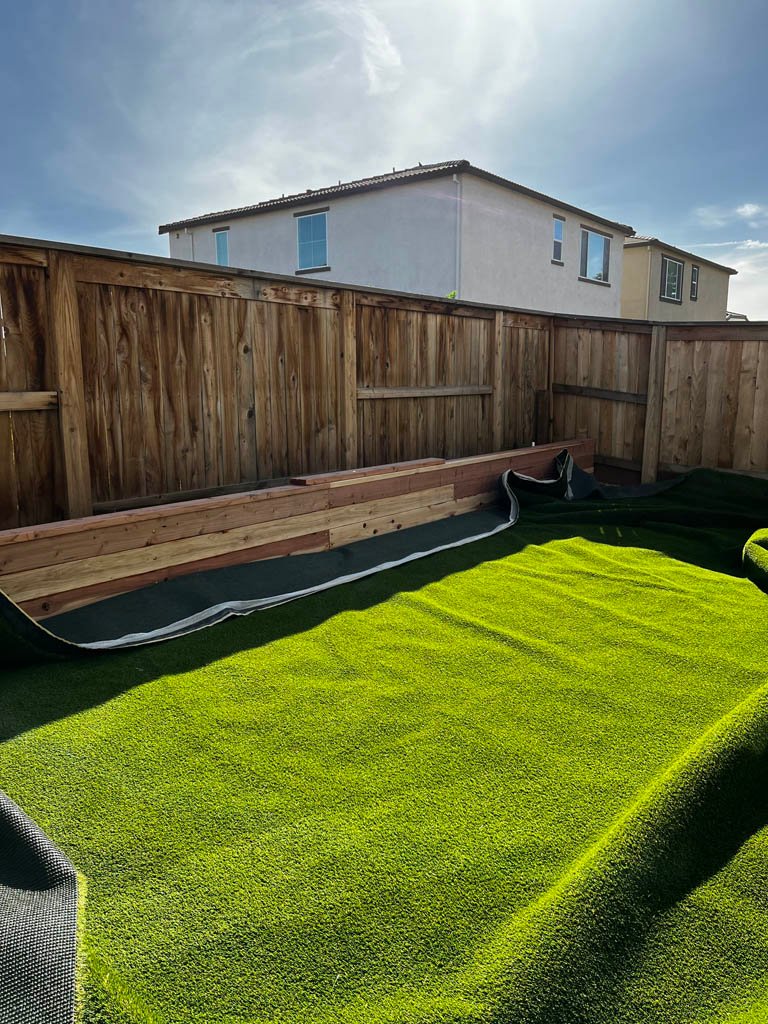 Backyard with artificial turf and wooden fence.