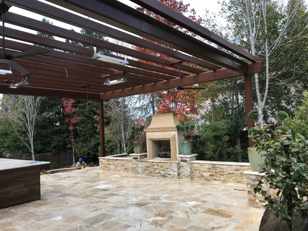 Outdoor patio with pergola and stone fireplace.