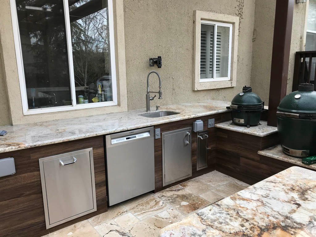 Outdoor kitchen with sink, dishwasher, and dual grills.