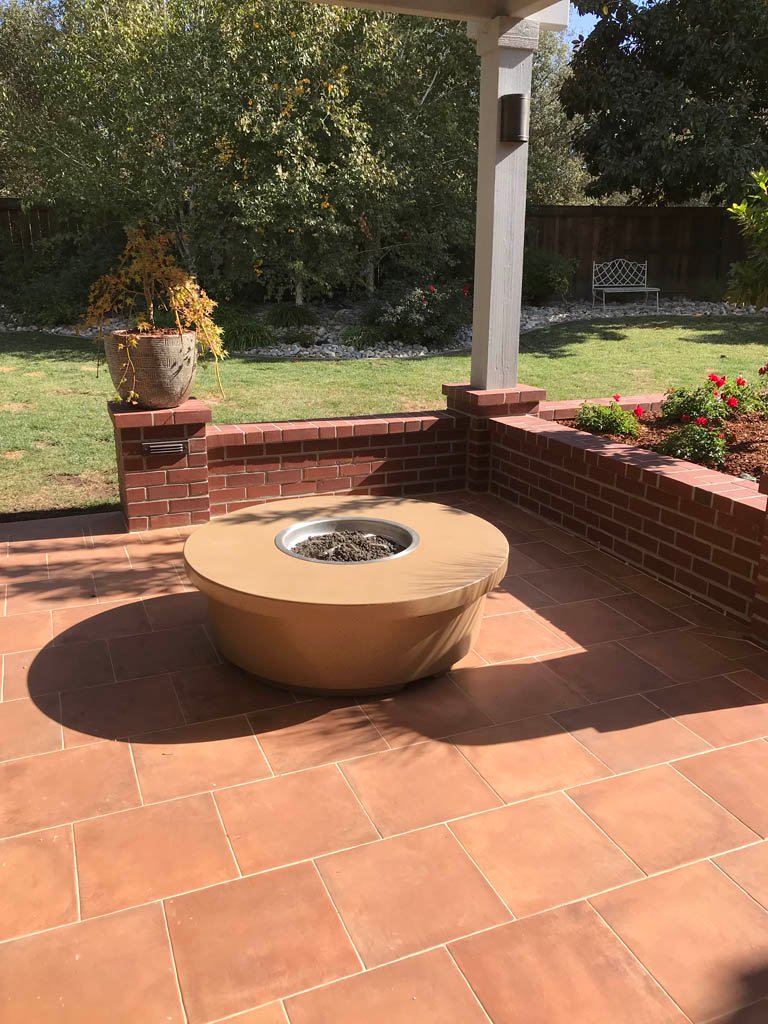 Sunlit patio with fire pit and garden view.