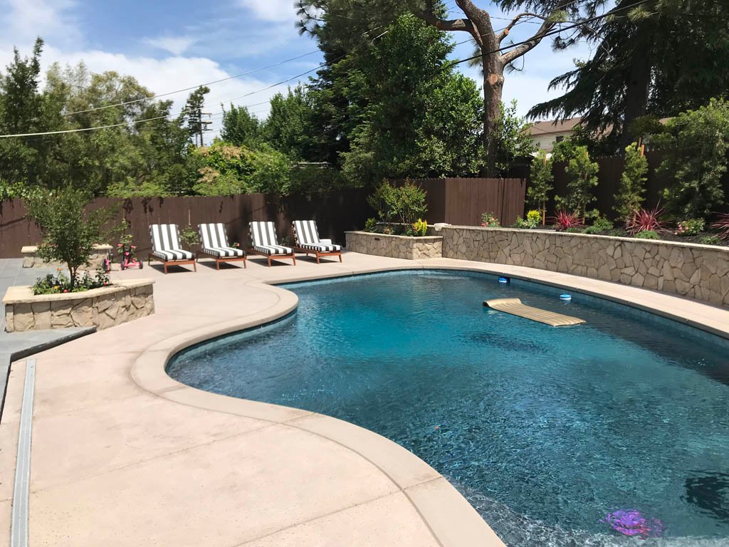 Sunny backyard with luxurious swimming pool and lounge chairs.