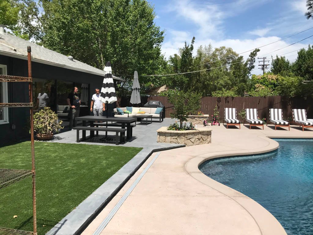 Lush backyard with pool, lounge chairs, and outdoor furniture.