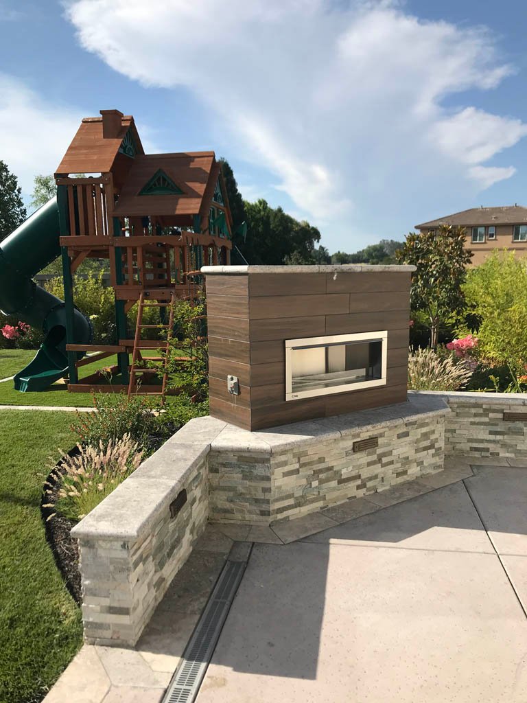 Outdoor playground with wooden playhouse and stone barbecue area.