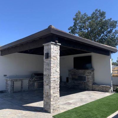 Outdoor kitchen pavilion with stone columns and modern appliances.