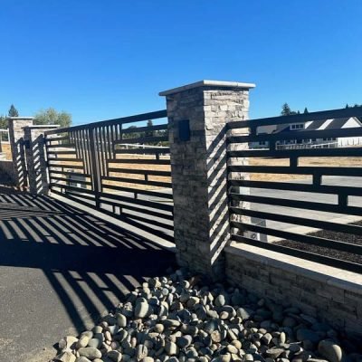 Stone pillar with wooden fence and pebble foreground