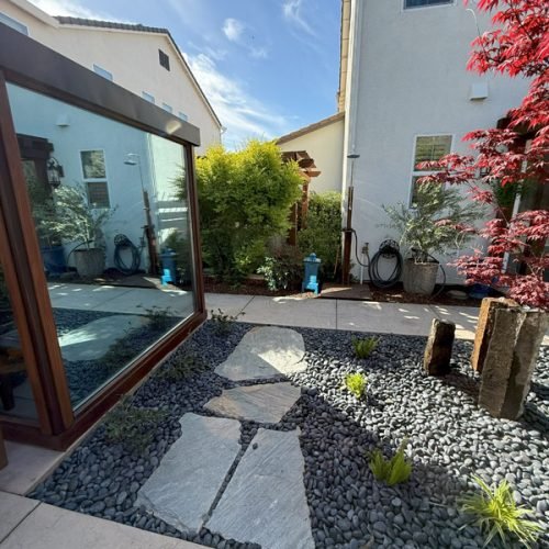 Beautiful backyard garden with stones and mirror by South Canyon Construction