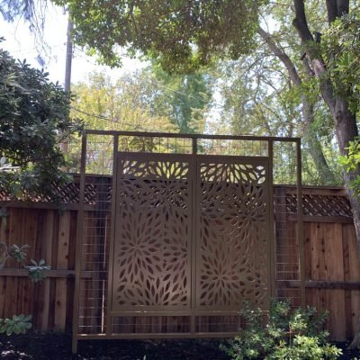 Decorative wooden garden screen among trees and shrubs.