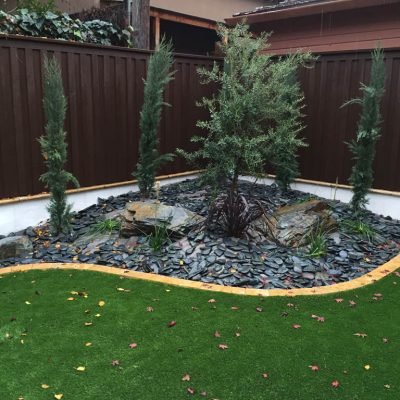 Residential garden with artificial grass and decorative stones.