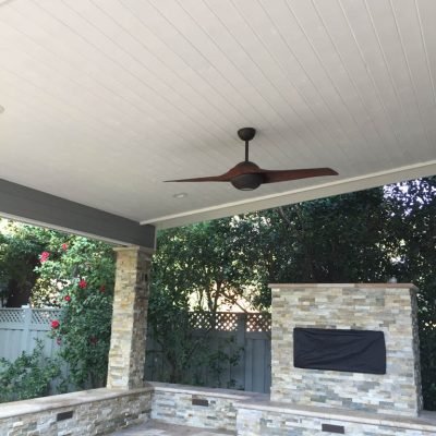 Covered patio with ceiling fan and stone fireplace.