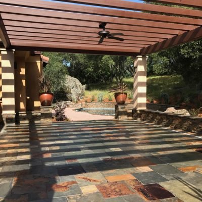 Pergola-covered patio with tiled floor and landscape view.