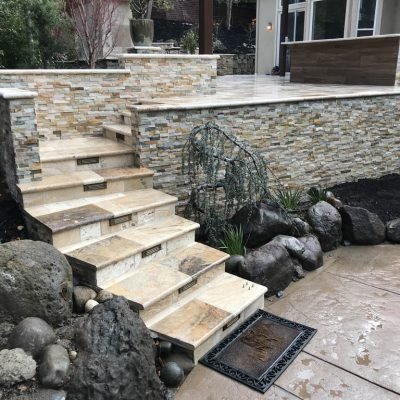 Stone outdoor staircase and wall with landscaped garden.