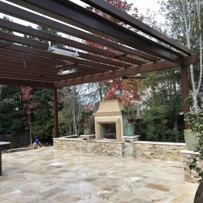 Outdoor patio with pergola and stone fireplace.