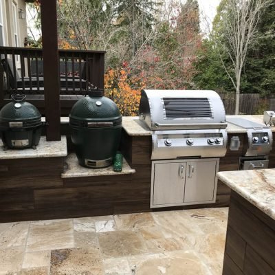 Outdoor kitchen with grills and autumn trees in background.