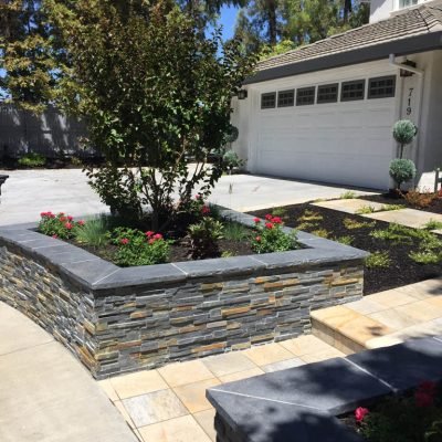 Landscaped front yard with stone walls and driveway.