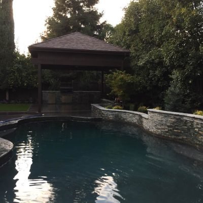 Gazebo by tranquil outdoor pool at dusk.