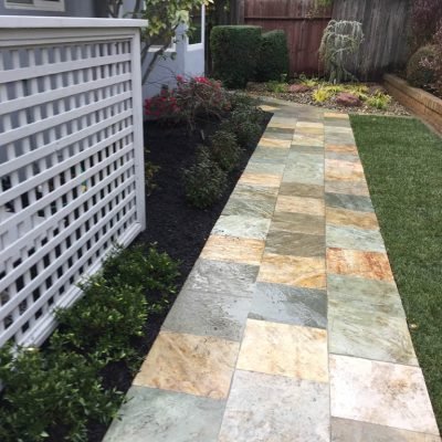 Pathway in landscaped garden with multicolored tiles.