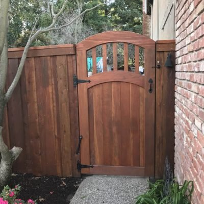 Wooden garden gate with arch and iron hardware.