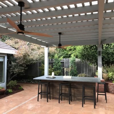 Spacious outdoor patio with overhead pergola and ceiling fans.