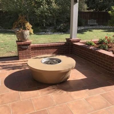 Sunlit patio with fire pit and garden view.