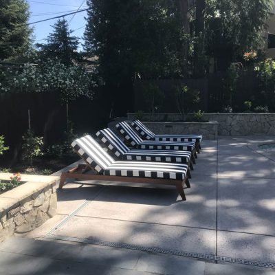 Sunny backyard with striped loungers by pool.