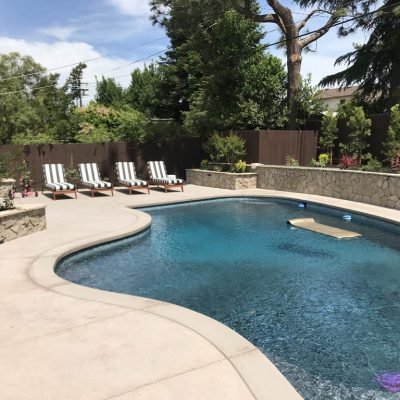 Sunny backyard with luxurious swimming pool and lounge chairs.