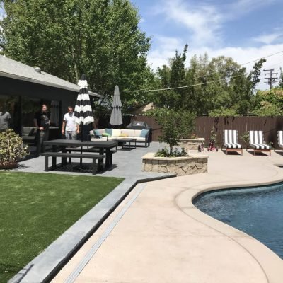 Lush backyard with pool, lounge chairs, and outdoor furniture.