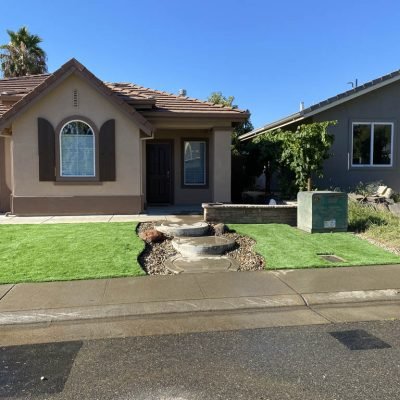 Suburban home with green lawn and decorative fountain.