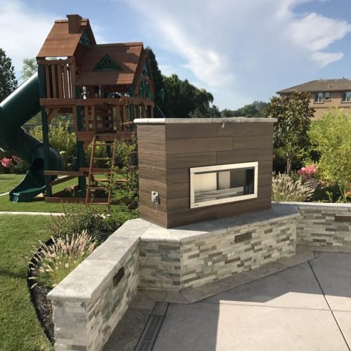 Outdoor playground with wooden playhouse and stone barbecue area.