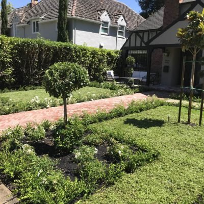 Tudor-style home with landscaped garden and brick pathway.