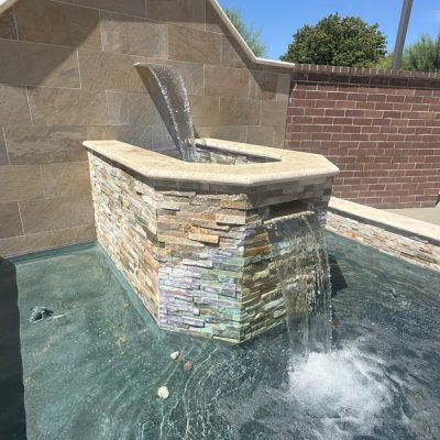 A stylish water feature built by South Canyon Construction showcases cascading water in a serene outdoor setting. The natural stone complements the tranquil atmosphere.