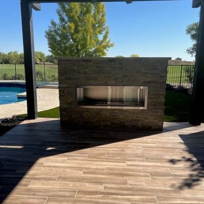 Outdoor covered patio with stone fireplace and pool view